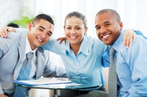 Three embraced businesspeople sitting and looking at the camera.